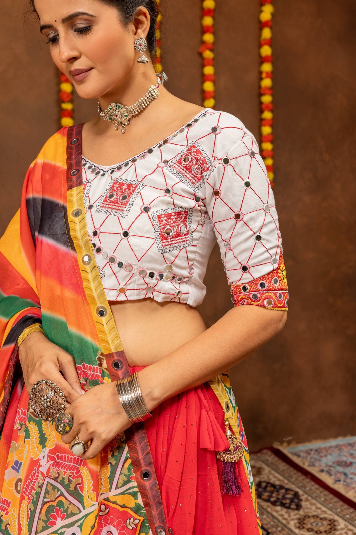 Close-up view of the white blouse showcasing red geometric embroidery patterns and round mirror embellishments.