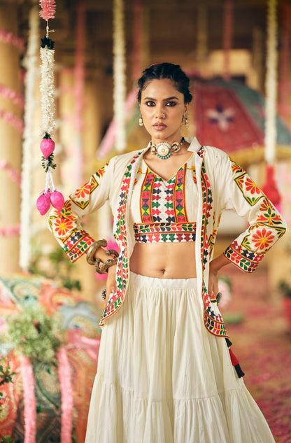 Mid-shot front view of model wearing a geometric embroidered white crop blouse under an open full-sleeve embroidered jacket