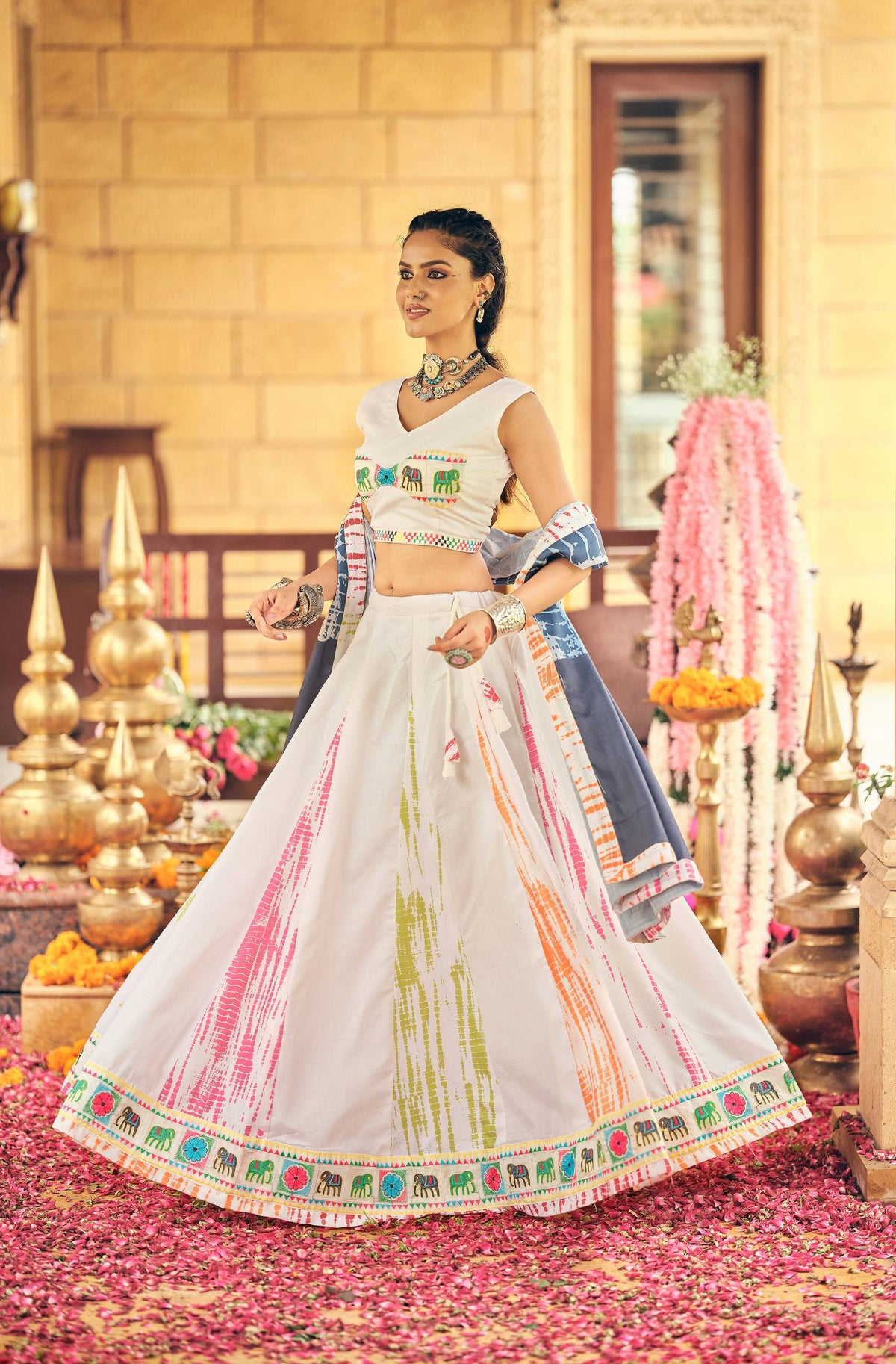 Standing full-length shot showcasing the wide flare and elephant border print of a white multicolor tie-dye lehenga