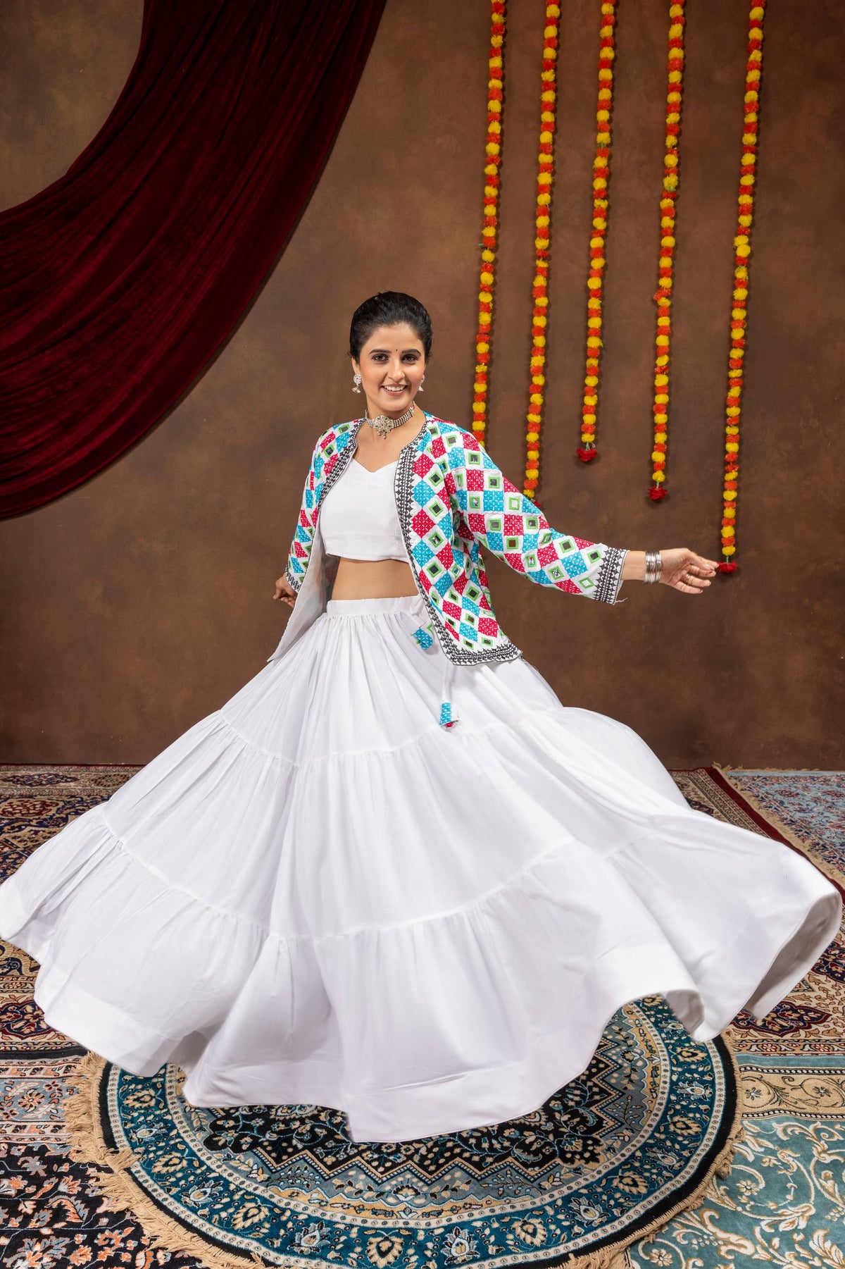 Low-angle twirling view of model displaying flared white tiered skirt and open front-slit jacket