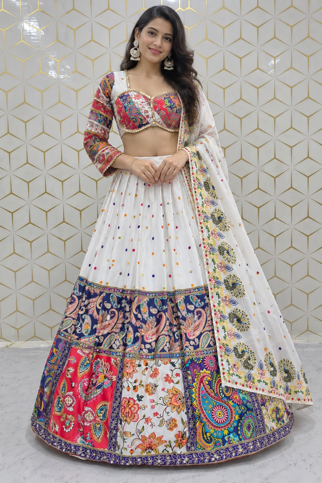 Standing full-length front view of a model wearing a white pleated lehenga featuring colorful polka dots and an ornate multicolor kalamkari paisley border.