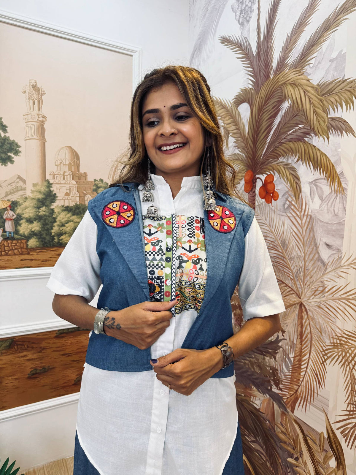 Mid-shot view highlighting the colorful folk embroidery on the white shirt chest and round patches on the blue jacket