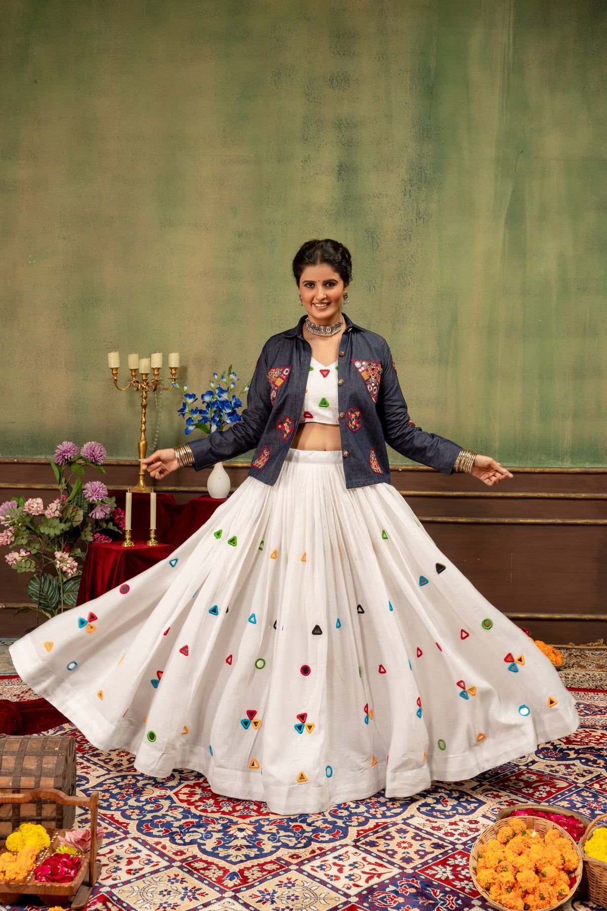 Full-length front view of model in white lehenga choli layered with a collared blue embroidered jacket