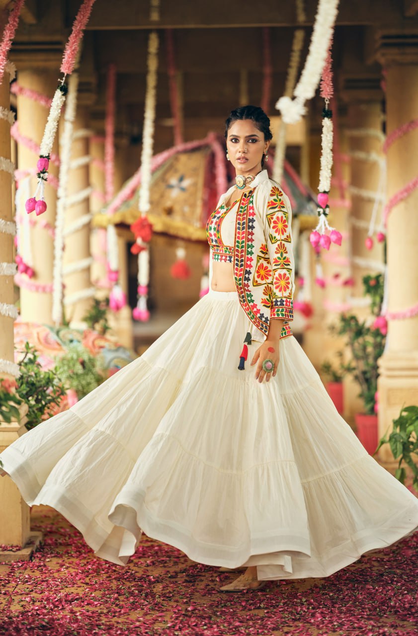 Full-length side view highlighting the wide gathered flare of a tiered white lehenga skirt and patterned white jacket