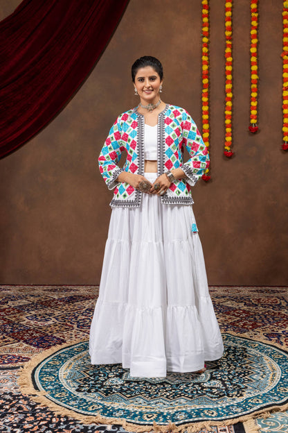 Full-length front view of model standing in white tiered lehenga choli set with open embroidered koti jacket
