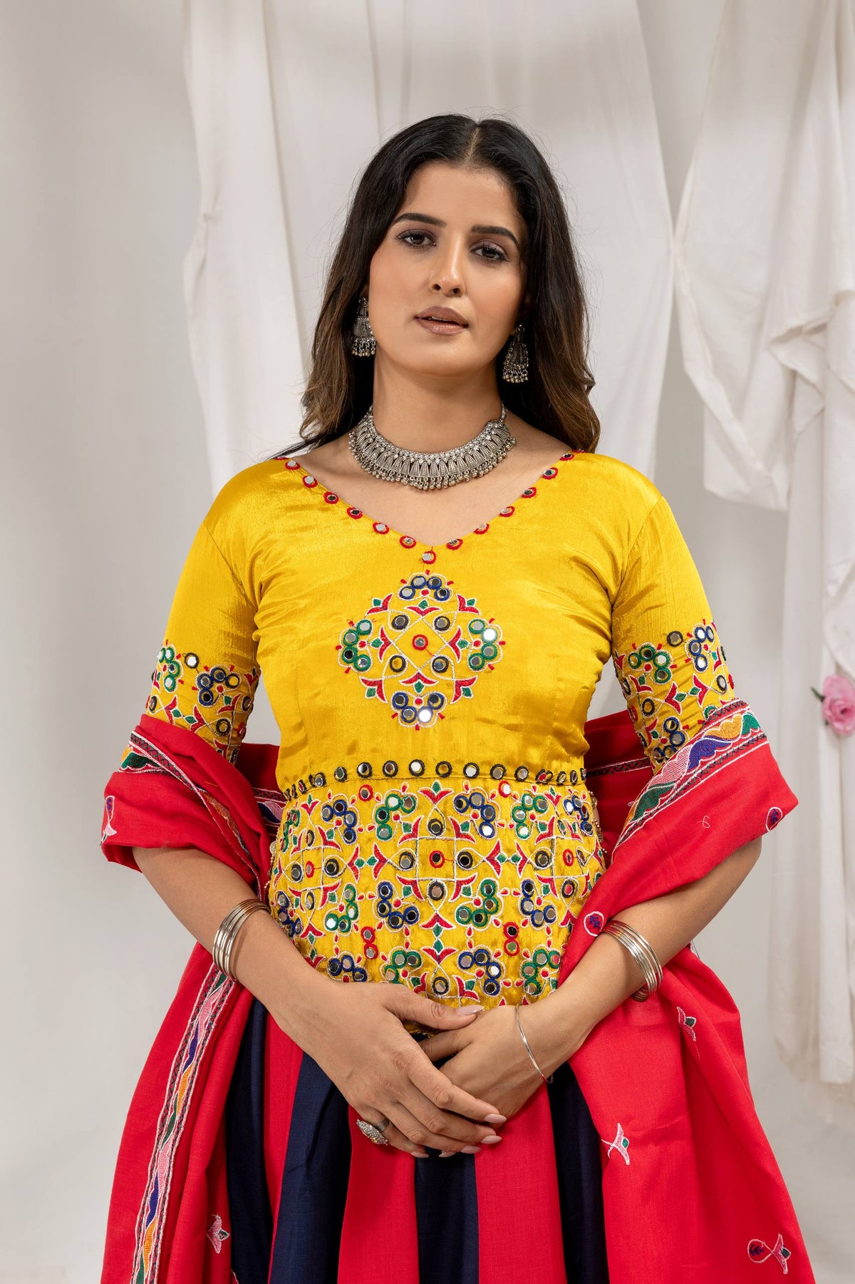 Close-up front view of yellow choli blouse featuring colorful mirror work embroidery and cowrie shell tassel fringe