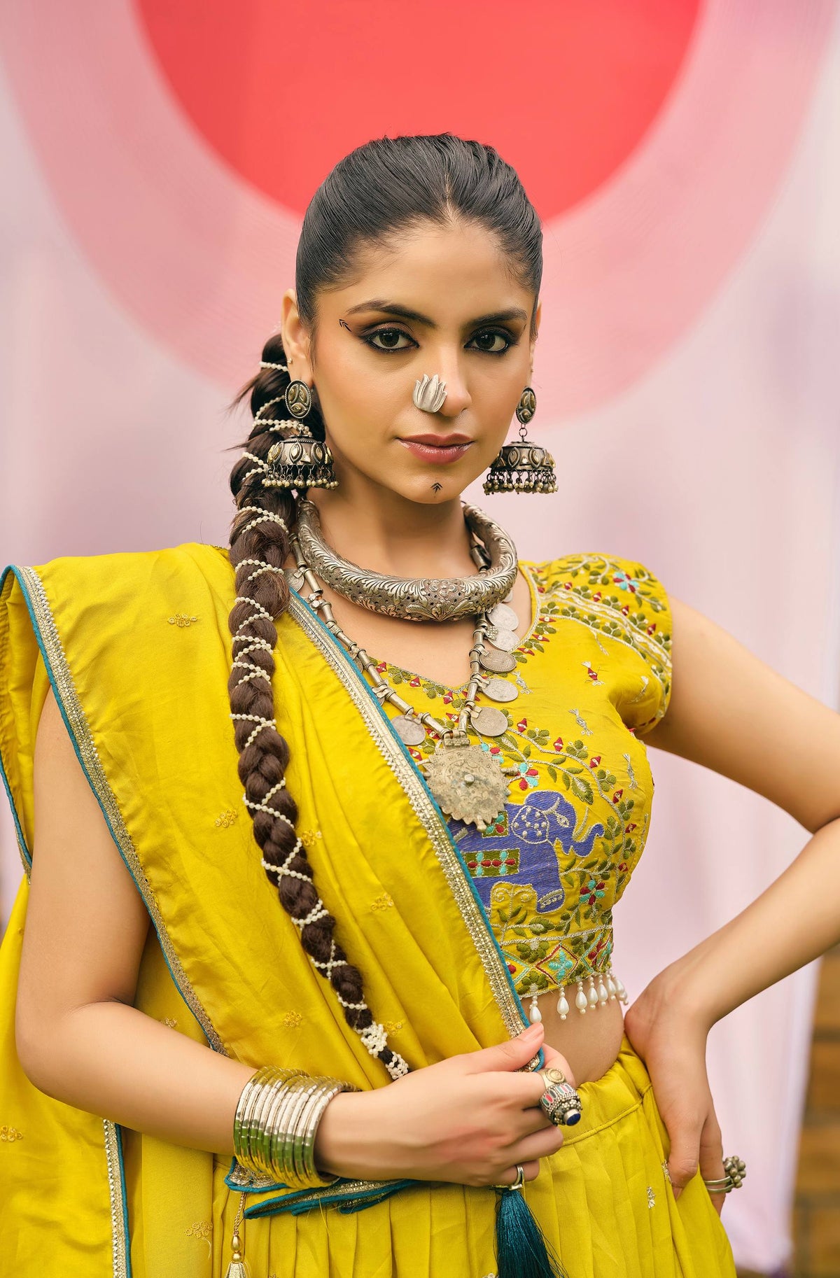 Close-up portrait of model wearing a yellow embroidered choli styled with a draped yellow dupatta and oxidized silver neckpiece
