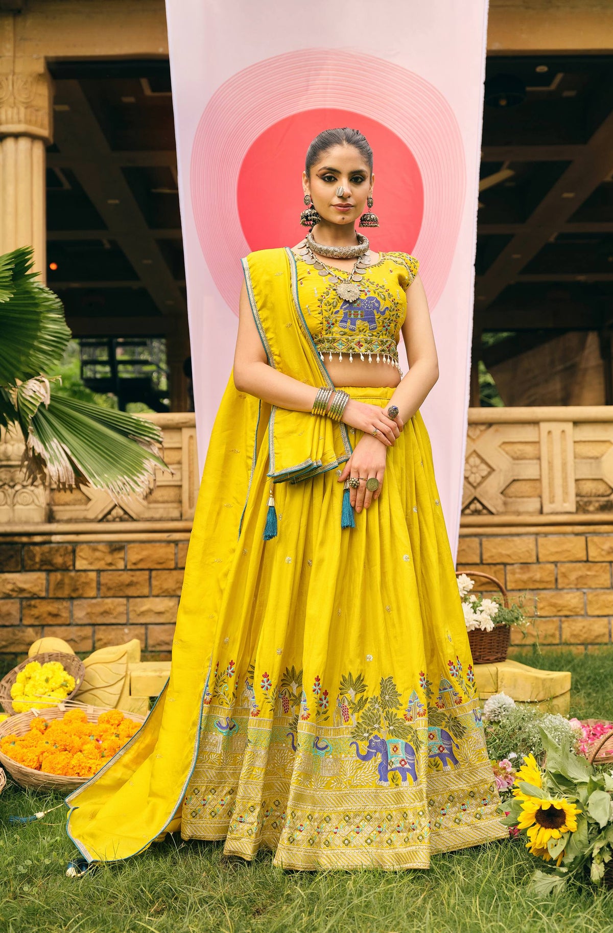 Full-length front view of a model wearing a pleated yellow lehenga choli set with matching draped dupatta