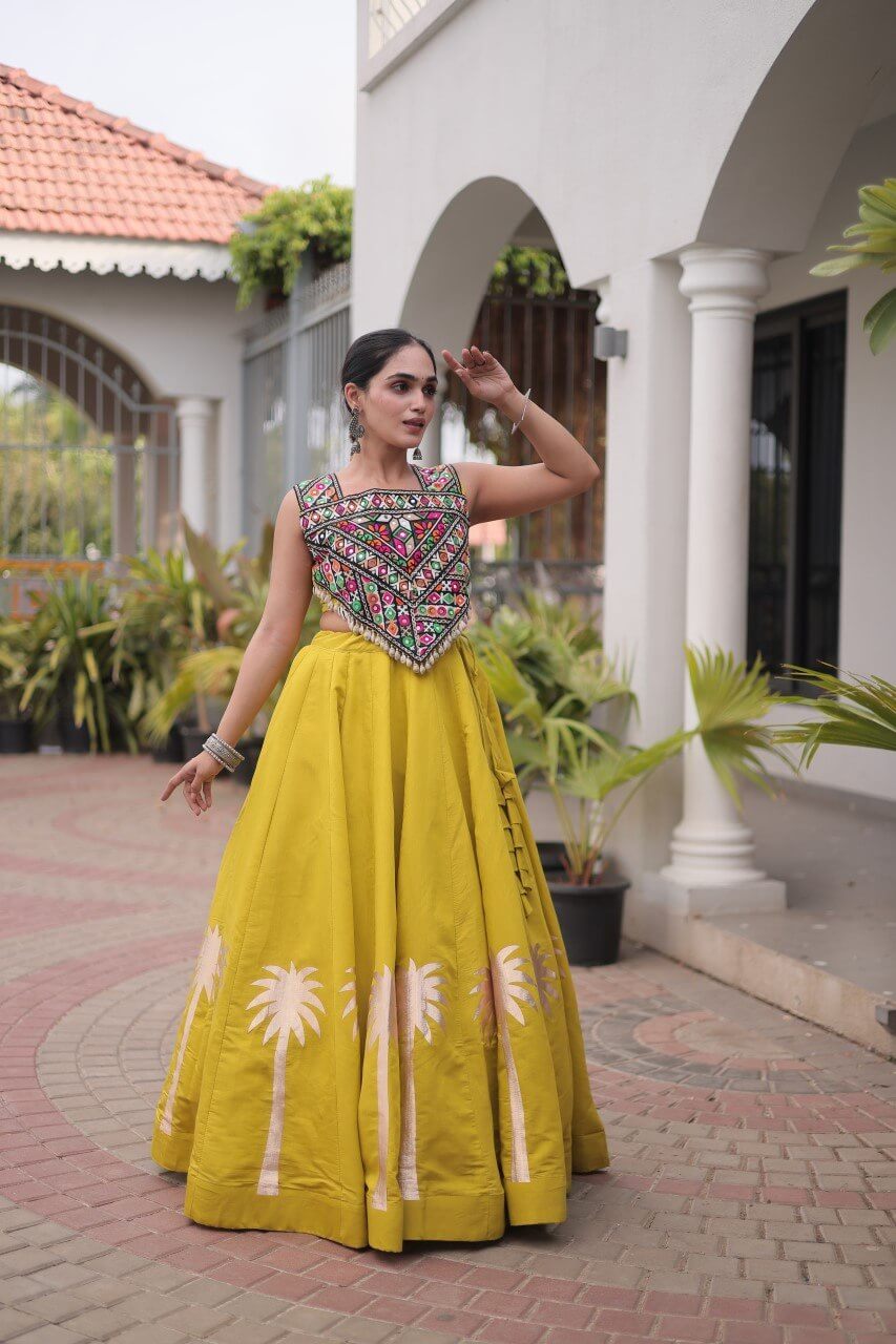 Yellow lehenga choli with multicolored embroidered blouse and floral skirt detailing in a side pose