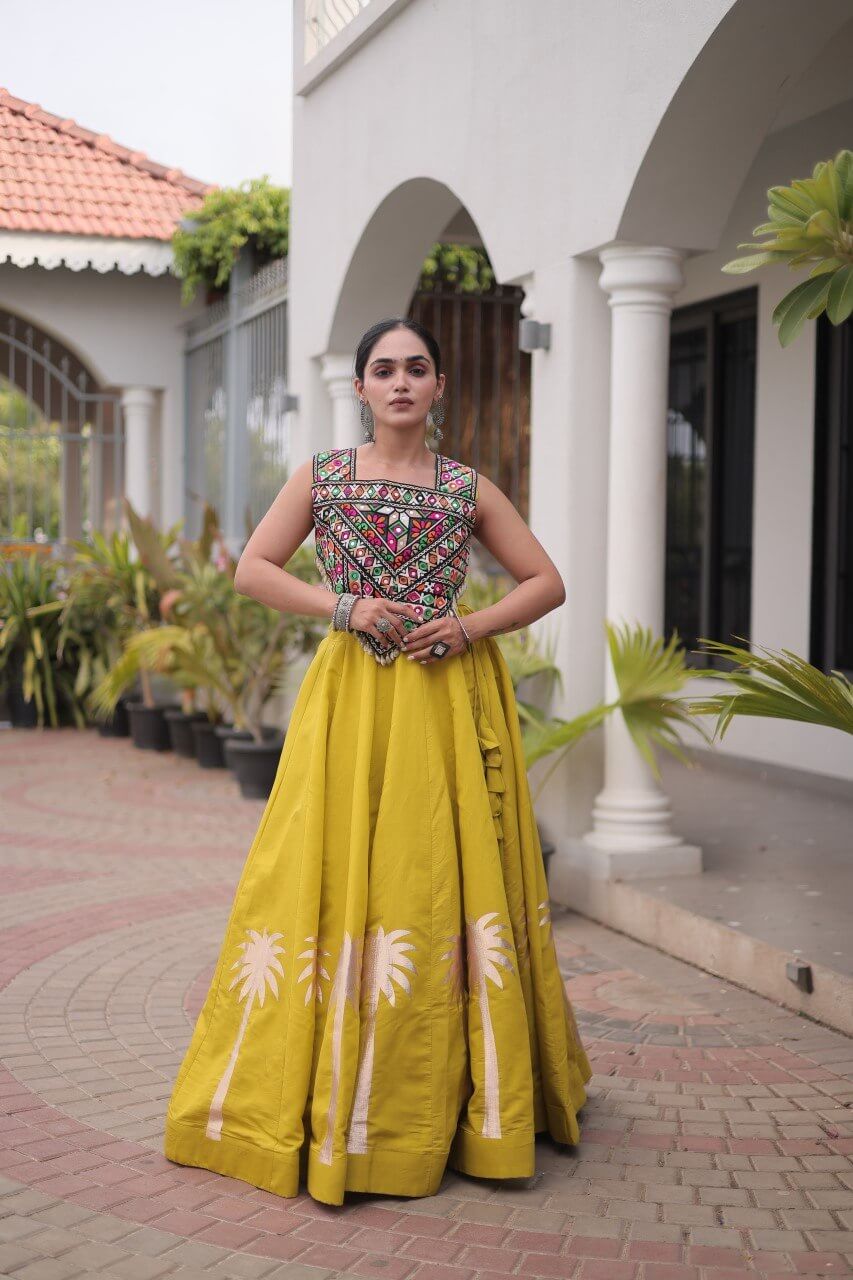 Yellow lehenga choli featuring a multicolored embroidered blouse and floral detailing along the skirt