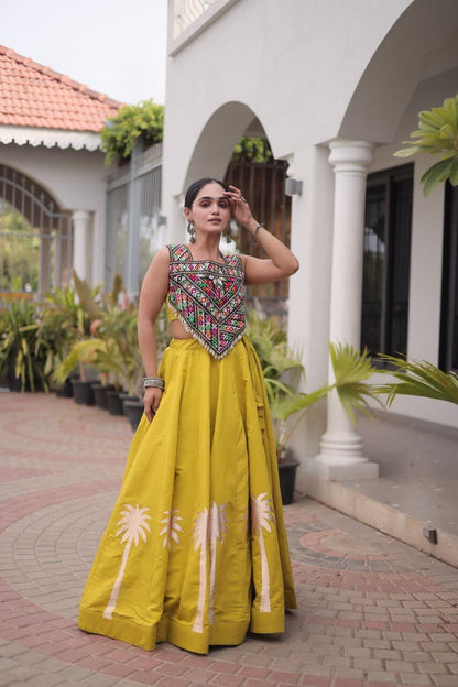 Yellow lehenga choli with multicolored embroidered blouse and floral skirt detailing in a standing pose