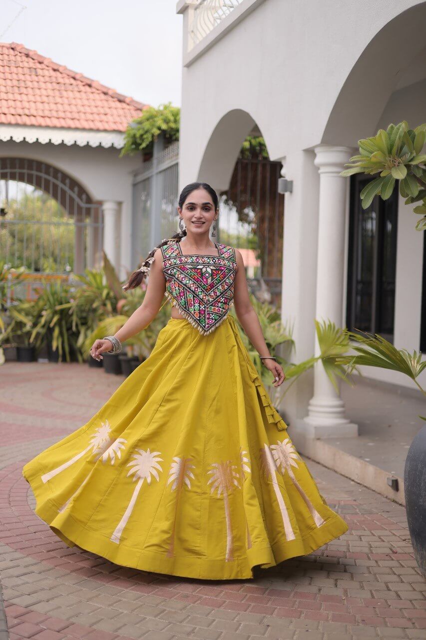 Front view of a yellow lehenga with a multicolored embroidered blouse and floral skirt detailing