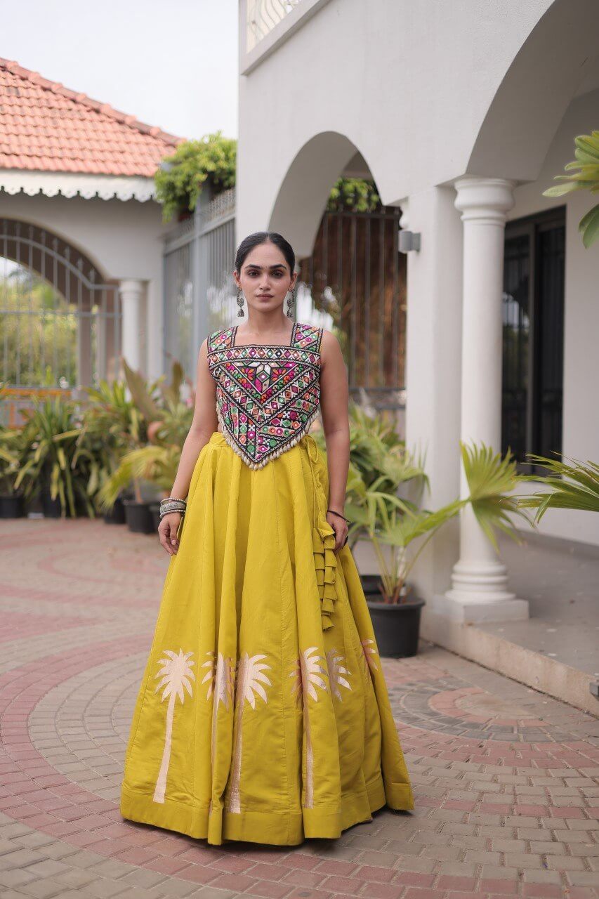 Front view of a yellow lehenga choli with multicolored embroidered blouse and floral skirt detailing