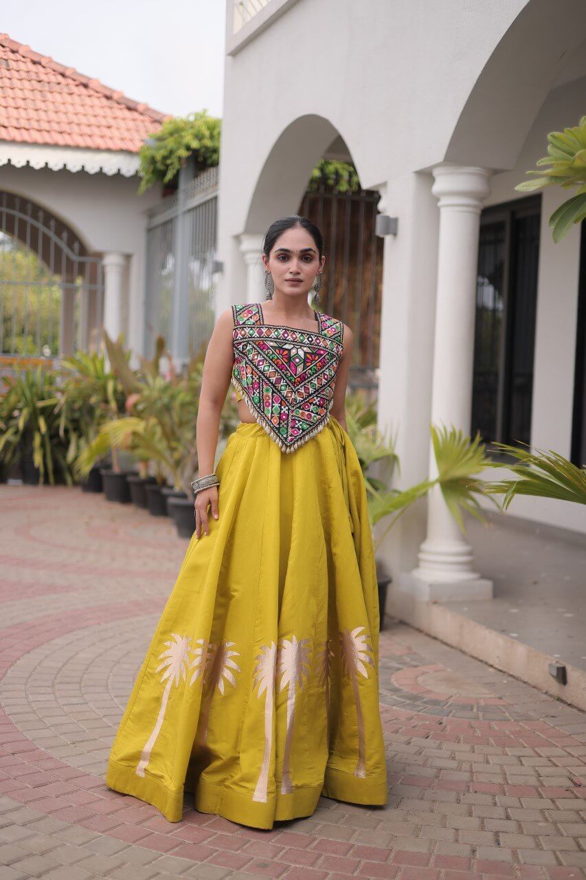 Front view of a yellow lehenga choli with multicolored patterned blouse and floral skirt detailing